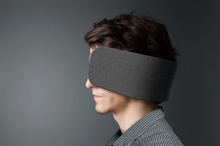 A man with a black blindfold covering his eyes, representing blindness or vision obstruction.