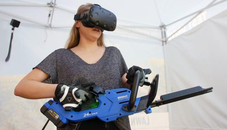 A woman wearing a virtual reality headset and using a handheld VR controller, standing in an outdoor tent setting