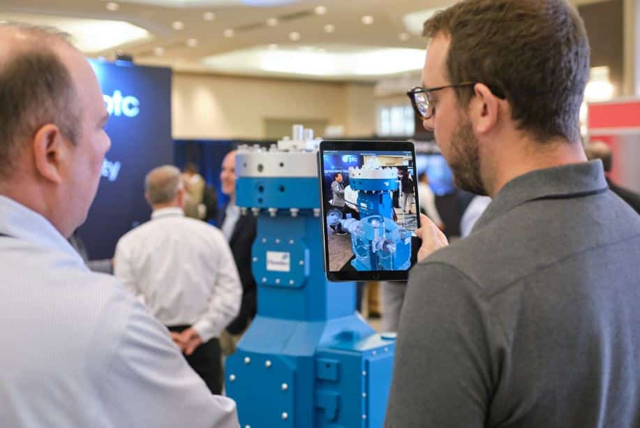 Two men examining a blue industrial machine on display at a trade show or conference
