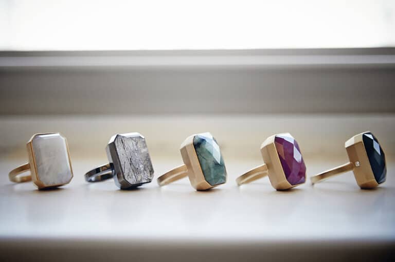 Assortment of unique, geometric rings with various natural stone settings on a white background