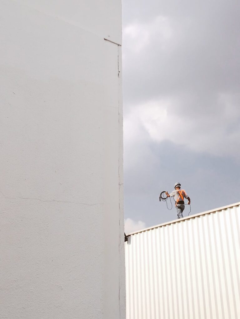 Worker on scaffolding maintaining exterior of building, with tools and safety gear
