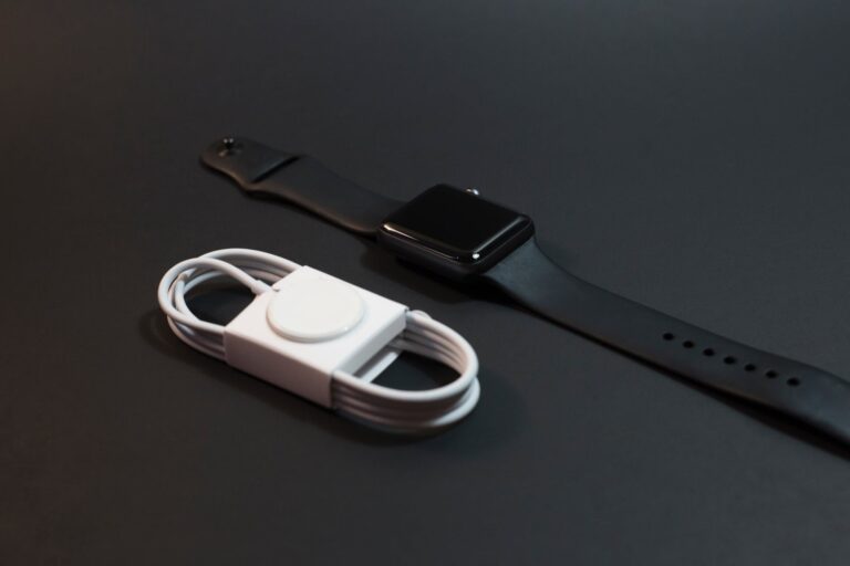 Black smartwatch and white charging cable on dark background