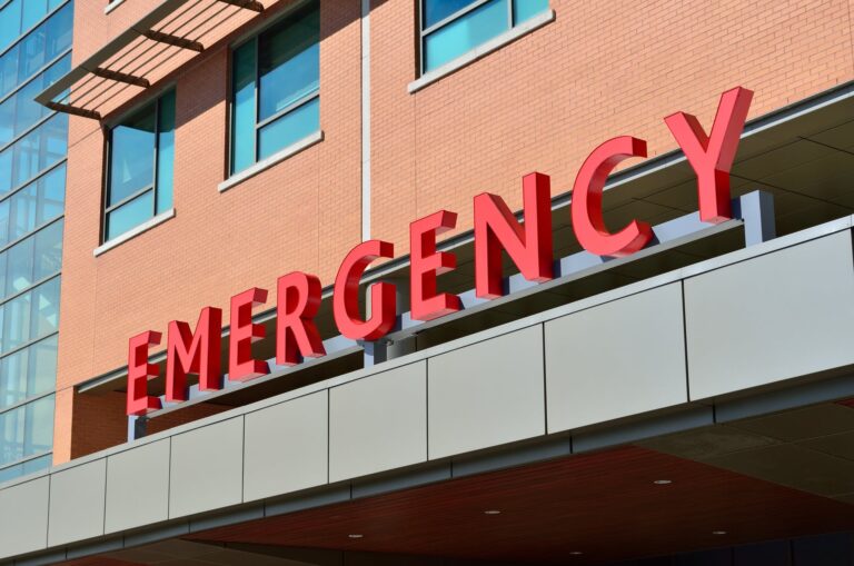 Large red 'Emergency' sign on the exterior of a brick building
