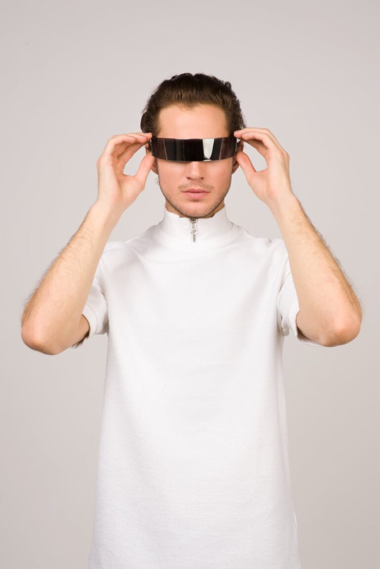 Person wearing futuristic black visor, standing in front of a plain white background