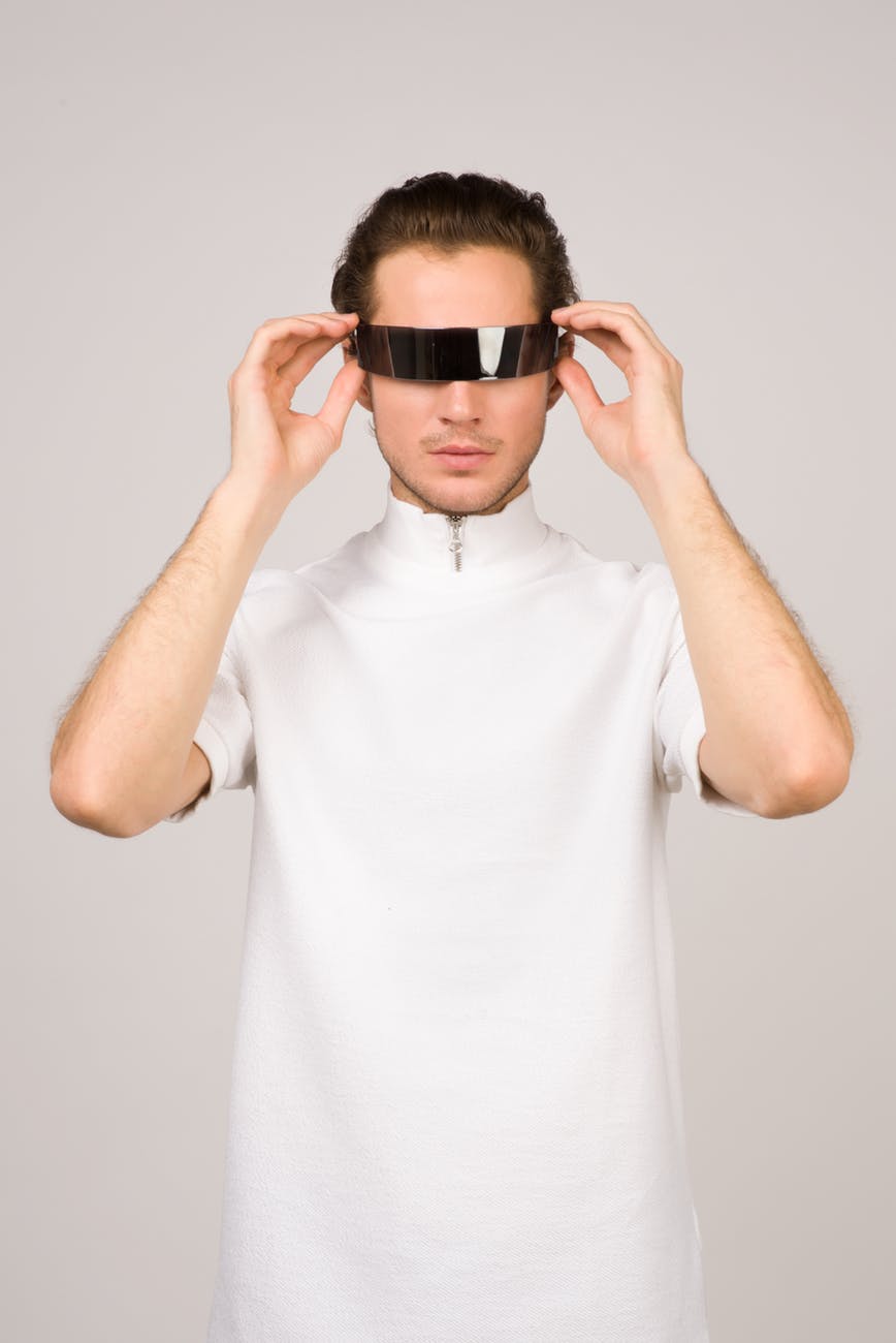 Person wearing futuristic black visor, standing in front of a plain white background