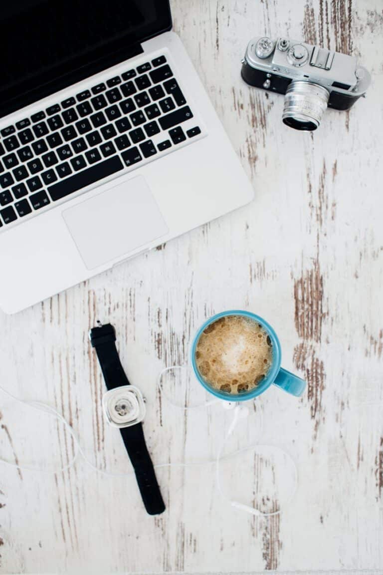 Laptop, camera, and coffee mug on rustic wooden table