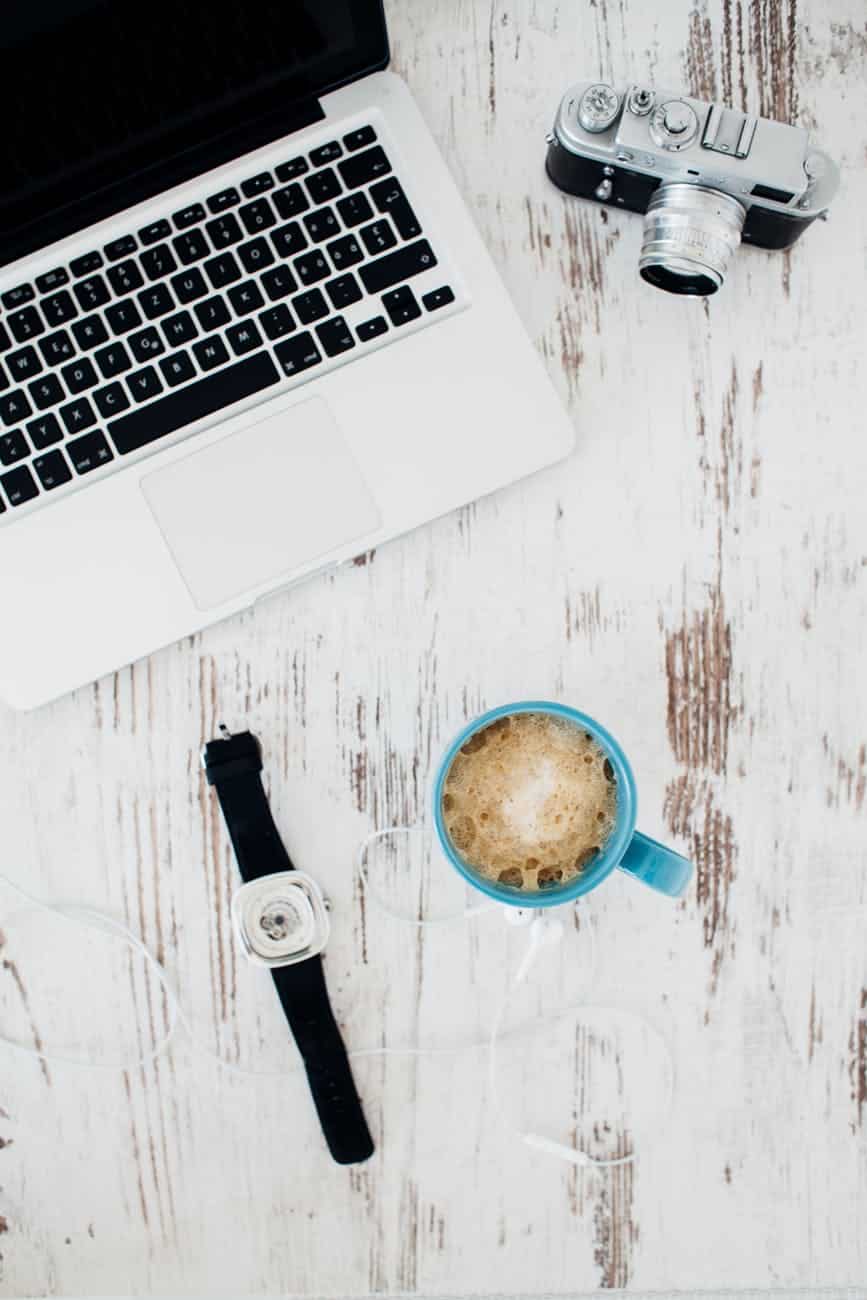Laptop, camera, and coffee mug on rustic wooden table