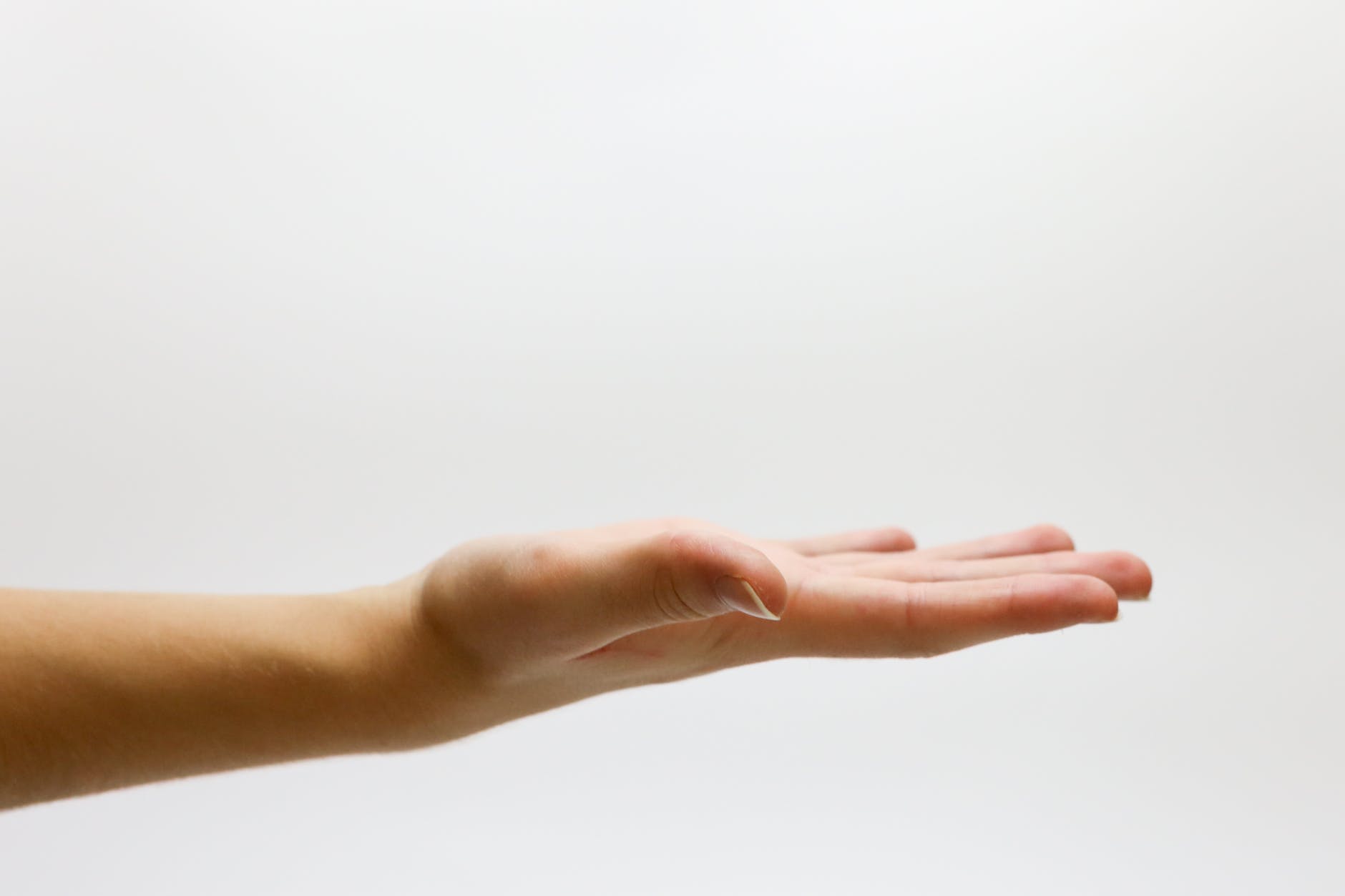 Hand gesturing in an open palm position against a white background