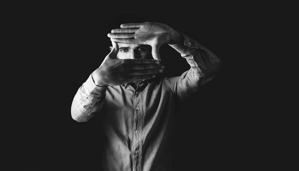 Black and white image of a person covering their face with their hands, suggesting privacy or concealment