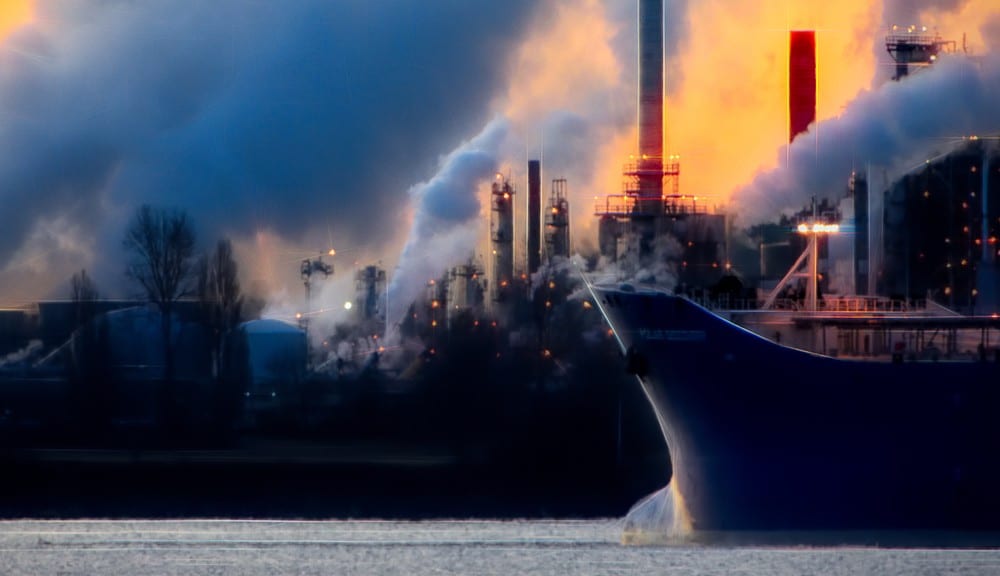 Dramatic industrial landscape with steam and smoke billowing from factory towers