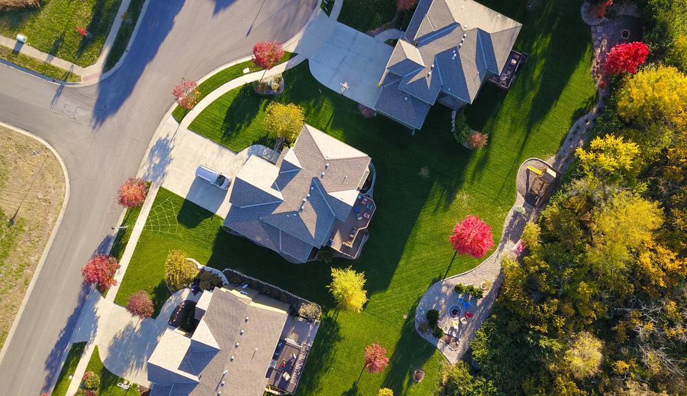 Aerial view of a residential neighborhood with houses, green lawns, and colorful trees