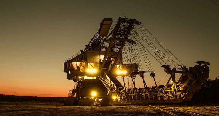 Massive industrial mining equipment in a field at sunset