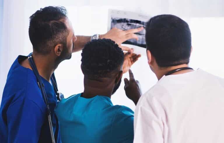 Three medical professionals examining an X-ray image together