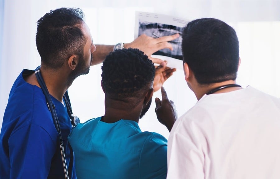 Three medical professionals examining an X-ray image together
