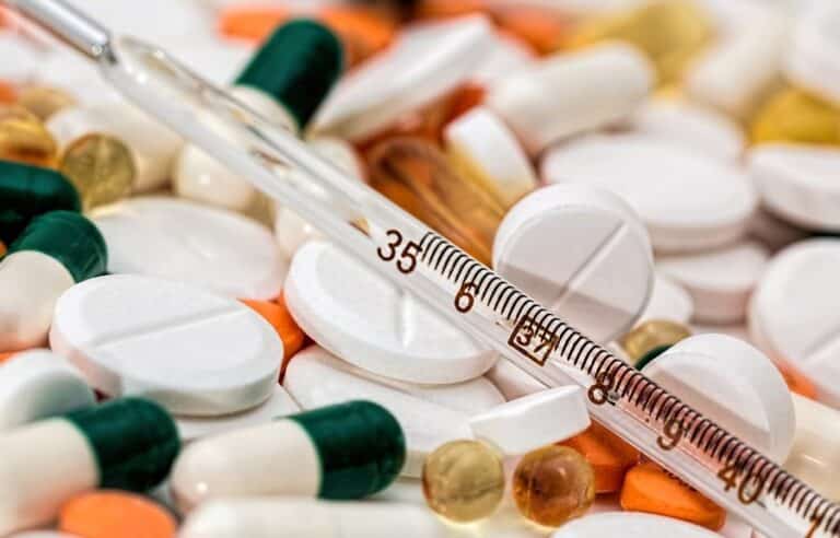 Assortment of colorful pills, capsules, and a medical thermometer with the number 35 displayed