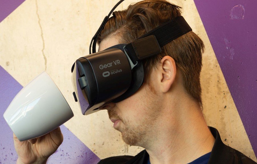 A man wearing a virtual reality headset, likely an Oculus Gear VR device, against a purple background