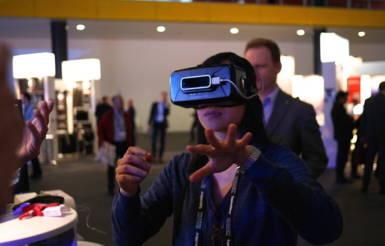 A man wearing a virtual reality headset, gesturing with his hands while experiencing a virtual reality demonstration at a technology expo
