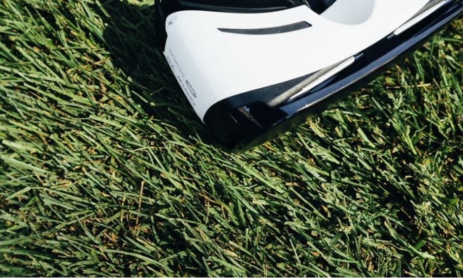 White and black golf club head in grass
