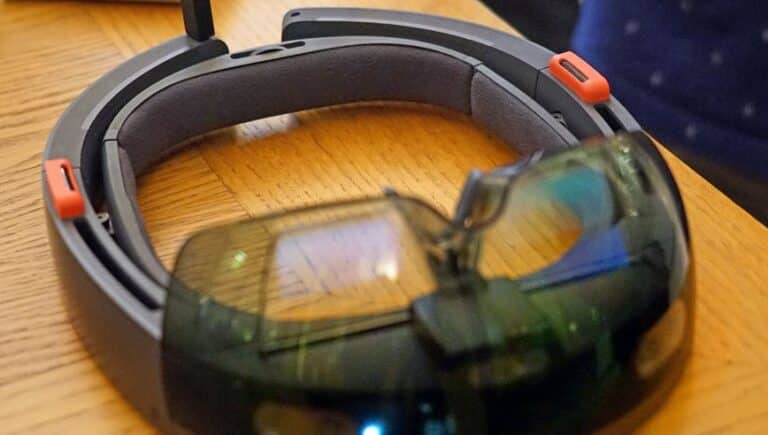Closeup of a virtual reality headset with colorful lenses, sitting on a wooden surface