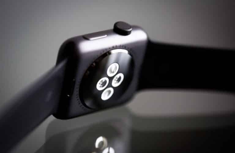 Close-up image of an Apple Watch with a black dial and silver casing, featuring buttons and controls on the side.