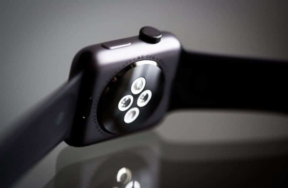 Close-up image of an Apple Watch with a black dial and silver casing, featuring buttons and controls on the side.