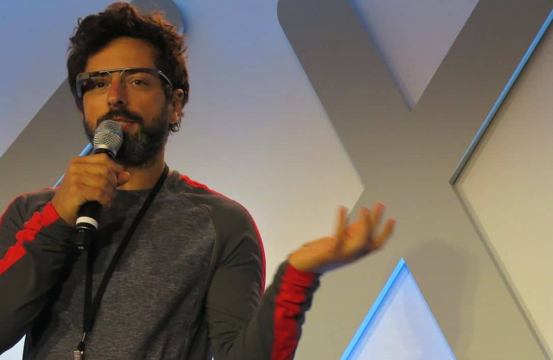 Man with a beard speaking into a microphone at a conference or event