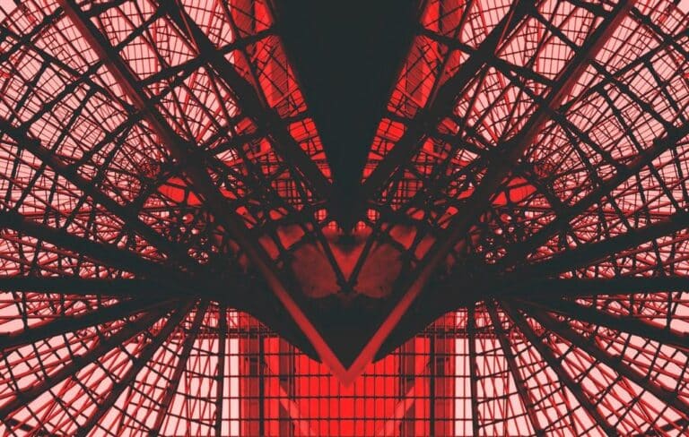 Abstract architectural structure in dark silhouette against a vibrant red background