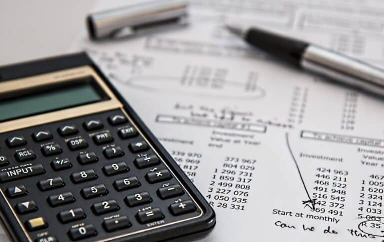 Calculator, pen, and financial documents on a desk, representing accounting and financial analysis work