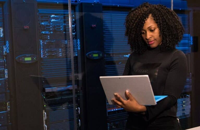 A woman with curly hair using a laptop in a data center