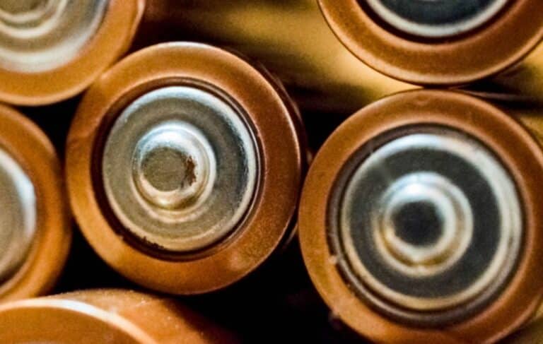 Close-up of various used batteries, some of which are copper-colored and cylindrical in shape, suggesting they may be AA or AAA batteries.