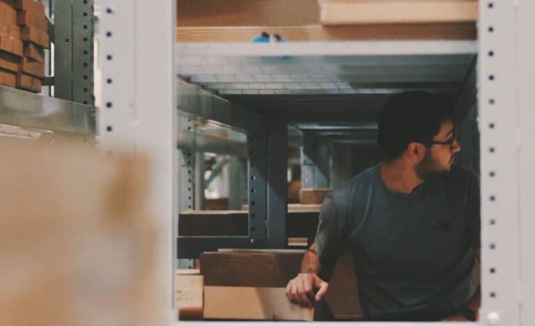 Man in a warehouse or storage area surrounded by shelving units and boxes