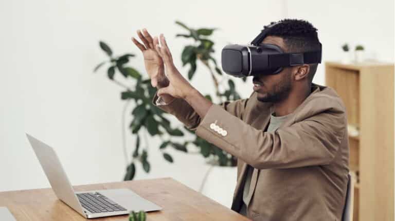 Man using virtual reality headset while working at a desk with a laptop
