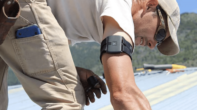 A person wearing work gloves and an action camera on their wrist, working on a construction site with tools and equipment in the background