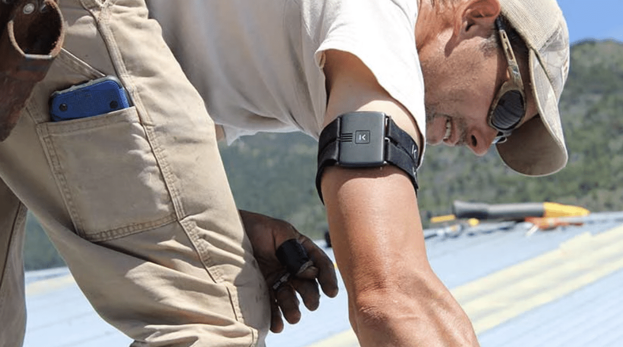 A person wearing work gloves and an action camera on their wrist, working on a construction site with tools and equipment in the background