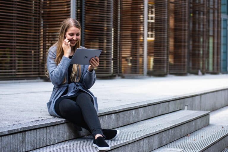 Young woman using a tablet device while sitting on steps outdoors