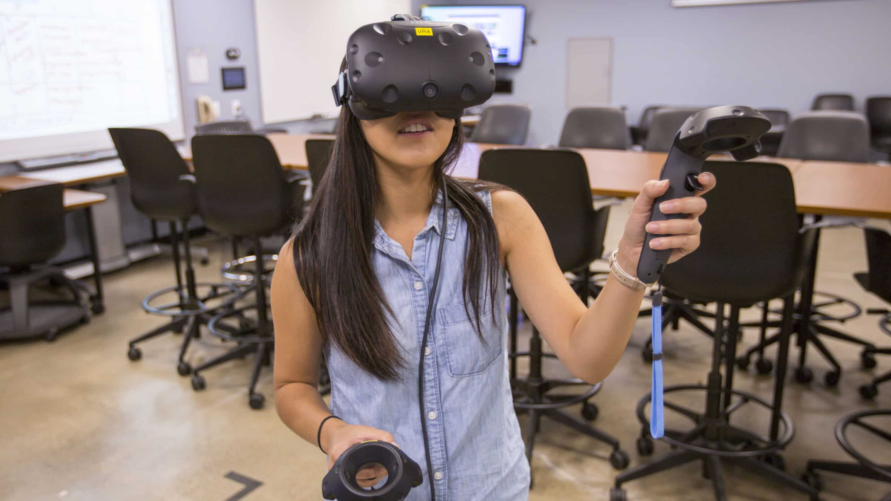 Person wearing VR headset and controller in classroom setting