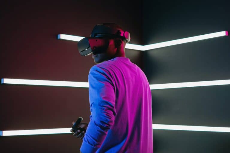A person wearing a virtual reality headset and holding a controller, surrounded by colorful lighting effects