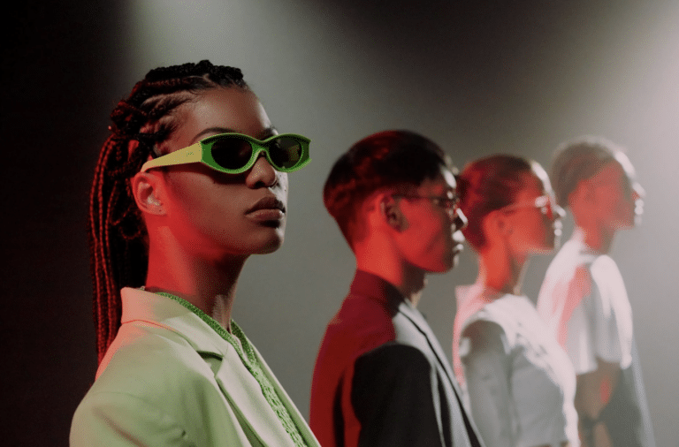 A group of young people posing on a dark stage, wearing stylish outfits and accessories.