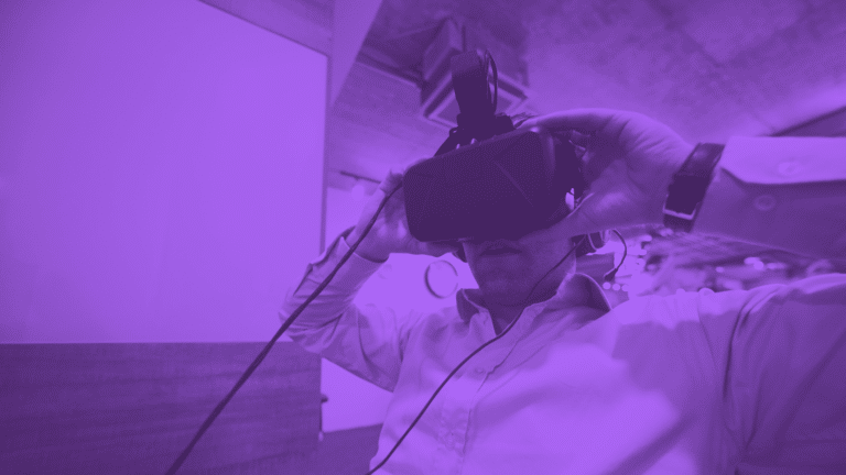 A person wearing a virtual reality headset in a dimly lit, purple-toned environment.
