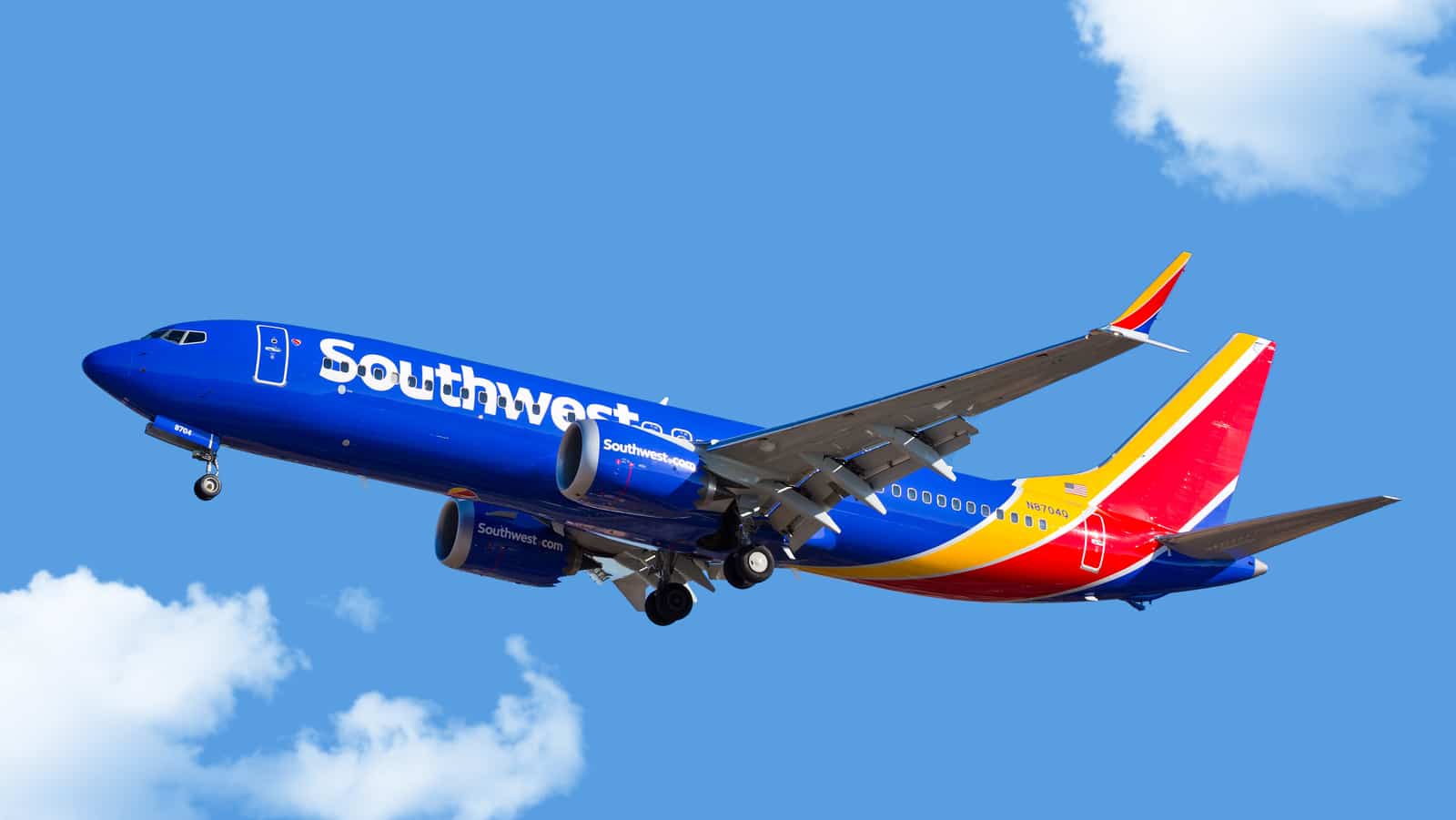 A Southwest Airlines passenger jet soaring against a blue sky with clouds