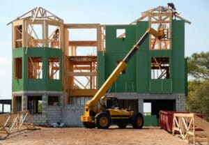 Construction site with wooden frame and yellow forklift, showcasing home building process