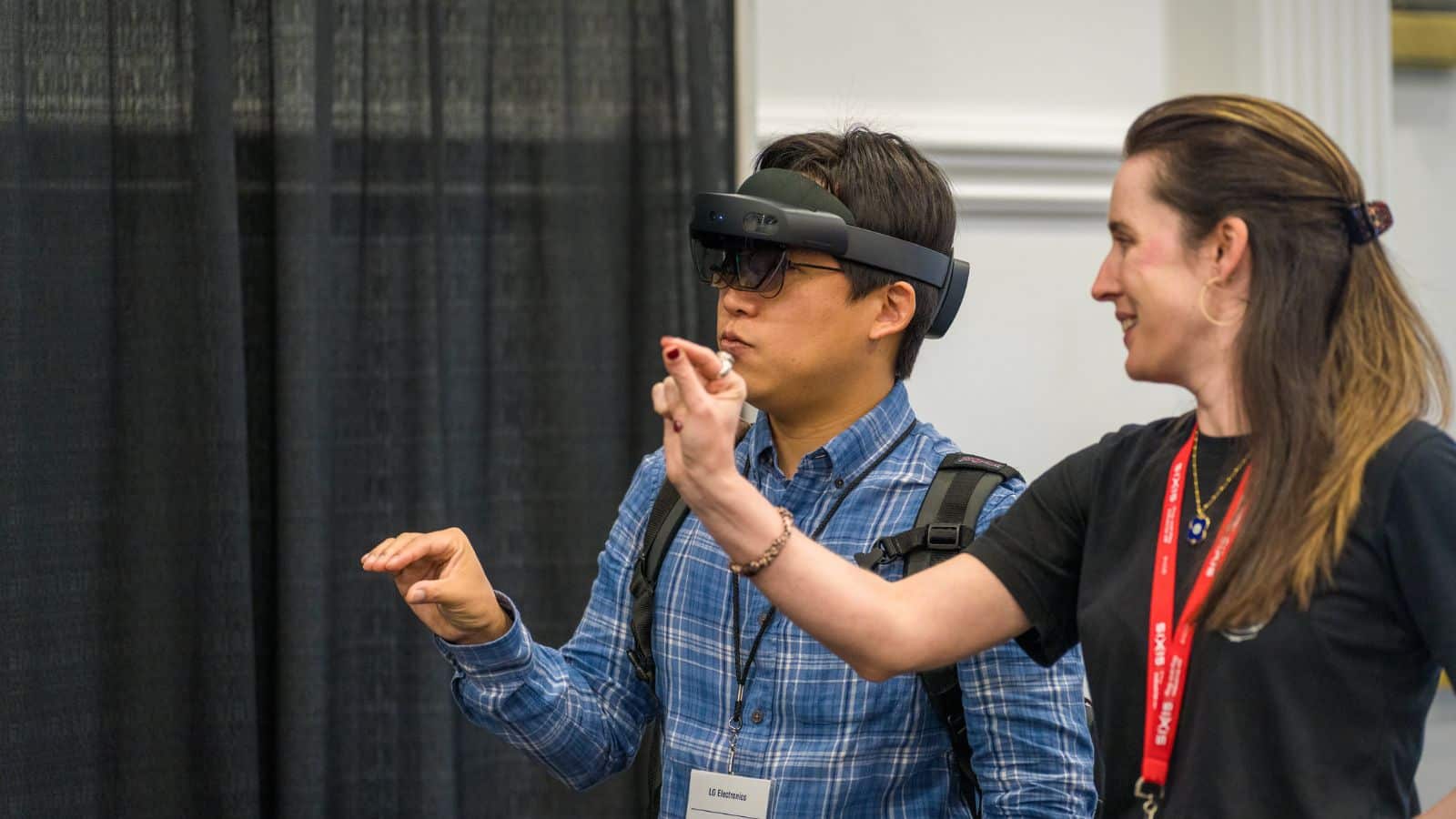 Two people interacting with virtual reality headset, one gesturing while the other observes