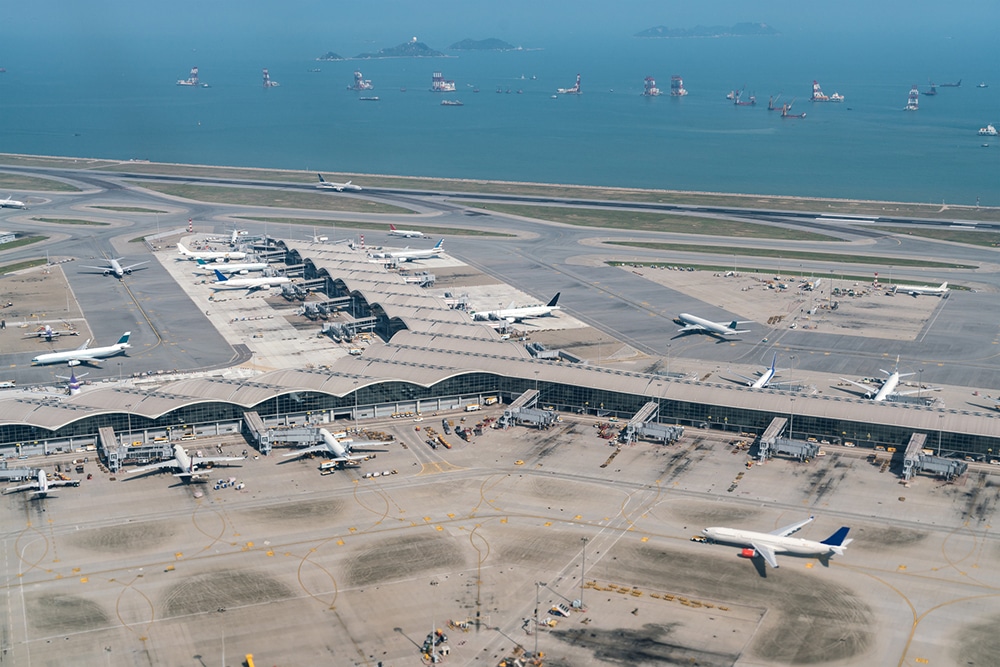 Aerial view of a bustling international airport with planes on the runway and terminal buildings