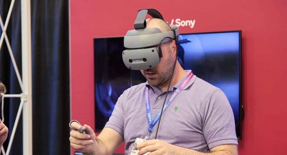 Man wearing virtual reality headset and controllers, using VR technology at tech event