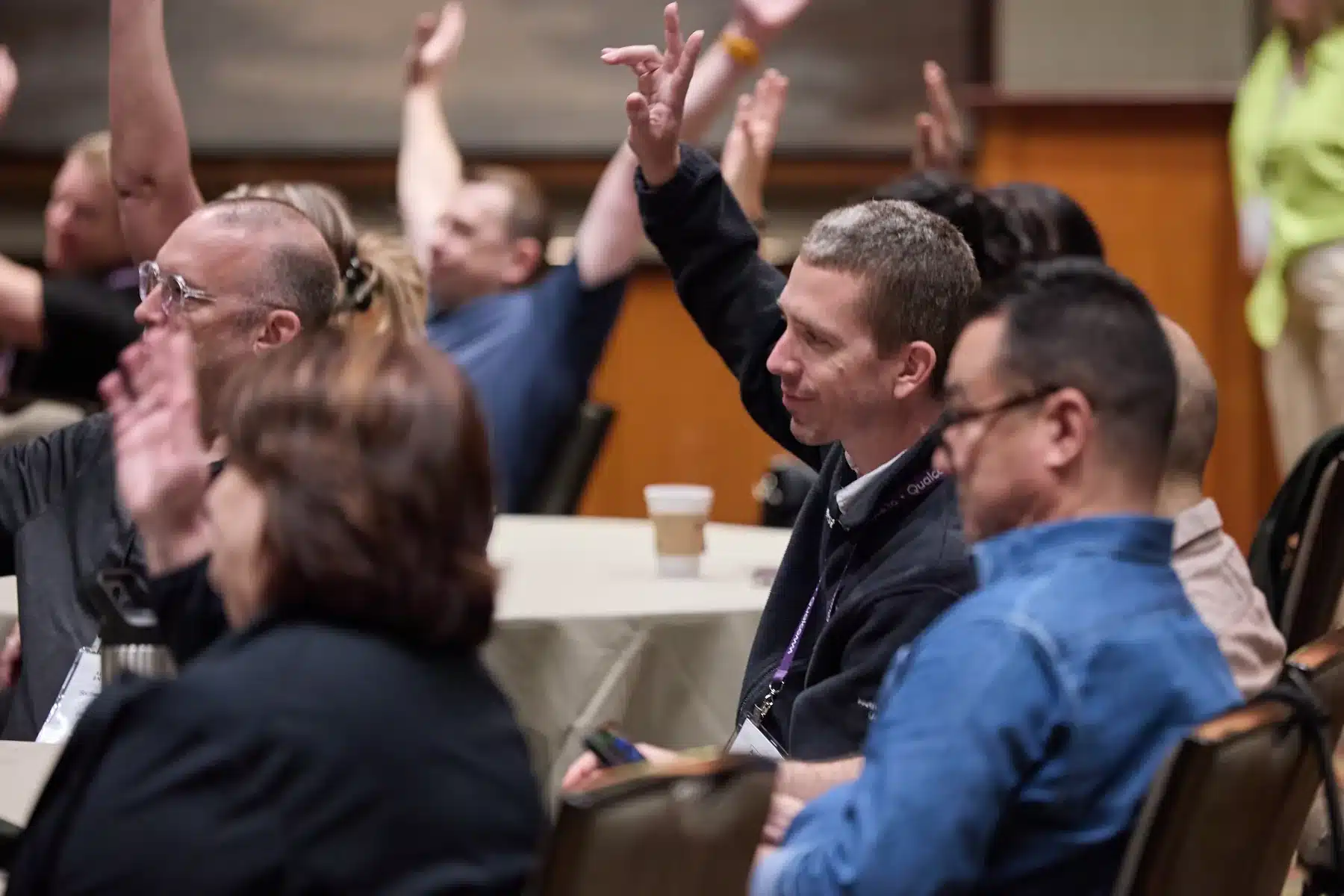 Attendees raising hands during a summit session